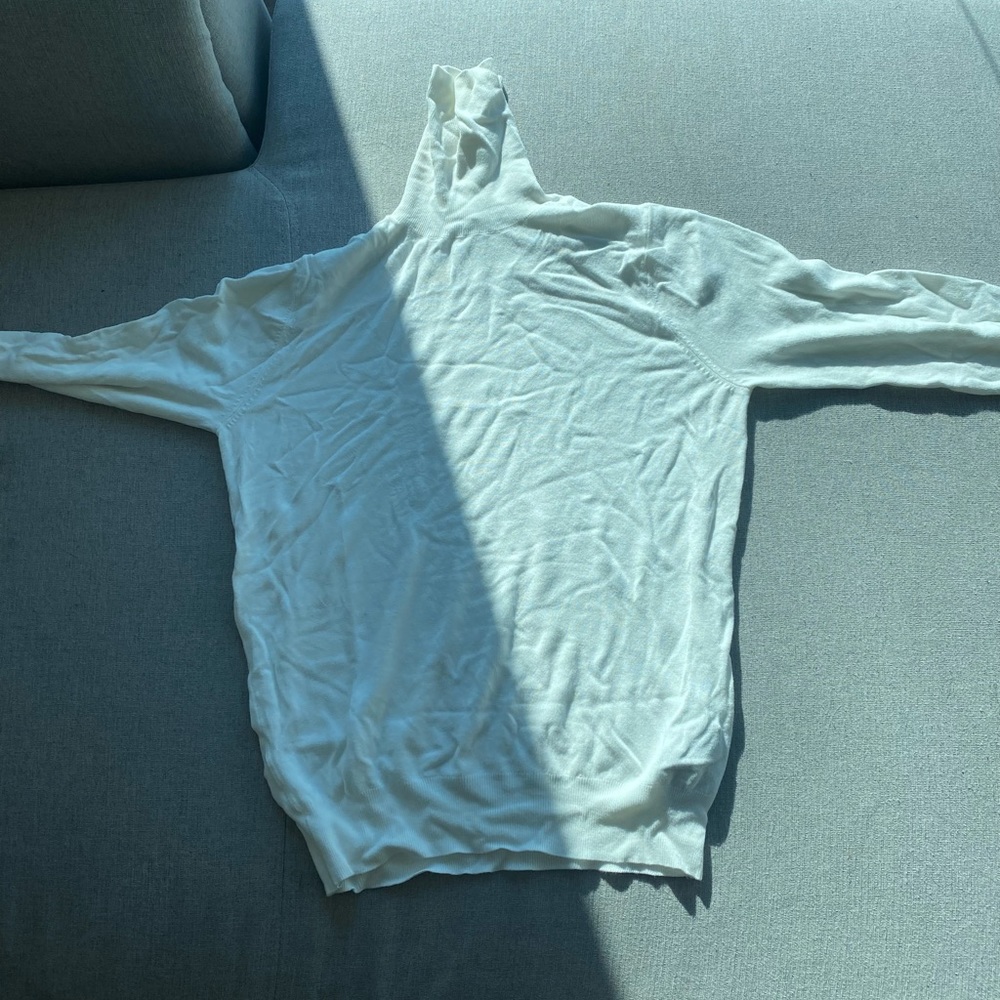 White turtleneck with gold button detailing on sleeves